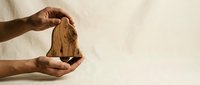 Hands gently holding wooden house model symbolizing home protection, real estate investment, property insurance and housing security concept.