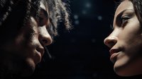 Dramatic close-up profile of two diverse women facing each other against dark background with bokeh light effects, conveying intimacy and emotional connection.
