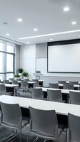 Modern conference room with projection screen and gray chairs arranged in rows for business meetings and corporate training sessions.
