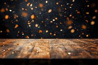 Rustic wooden table surface with magical floating orange bokeh lights and glowing particles against dark background, creating atmospheric mood for product display.