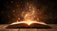 Open book with magical golden light and sparkling particles rising from pages creating mystical atmosphere on wooden surface against dark background.