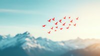 Red origami paper birds flying in formation against snowy mountain peaks and soft turquoise sky background, creating peaceful nature scene for wellness and freedom concepts.