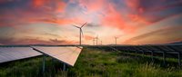 Solar panels and wind turbines generating clean renewable energy at sunset with dramatic orange sky and green landscape for sustainable power.