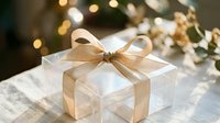 Elegant white gift box with golden ribbon bow on wooden table with warm bokeh lights and festive decorations creating cozy holiday atmosphere for celebrations.