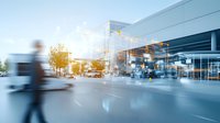 Blurred motion business people walking near modern office building with glass facade and autumn trees, urban cityscape with sunlight effect.