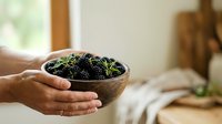 Hands holding wooden bowl filled with fresh green moss and soil, suitable for gardening, plant care, sustainability, and nature-based design projects.
