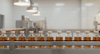 Modern whiskey distillery production line with amber bottles on conveyor belt in industrial facility for beverage manufacturing and quality control.