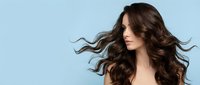 Young Caucasian woman with long flowing dark brown wavy hair against light blue background, hair care and beauty salon concept.