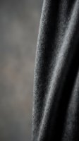 Close-up of soft gray knitted fabric texture with natural folds and draping, showcasing wool material detail for fashion and textile design projects.