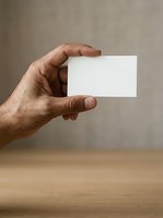 Male hand holding blank white business card against neutral background for branding and corporate identity mockup purposes.