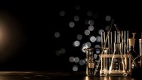 Laboratory glassware with golden bokeh lights on dark background for scientific research and chemistry experiments in modern lab setting.
