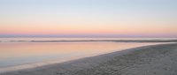Serene beach at sunset with gentle waves washing sandy shore under pastel sky creating peaceful coastal atmosphere for relaxation and meditation.