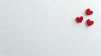 Red paper hearts on white background with copy space for Valentine's Day romantic design and love messages.