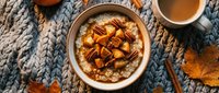 Creamy hummus topped with roasted chickpeas and paprika, served on a cozy knit fabric with autumn leaves and tahini sauce for dipping.