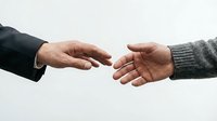 Two hands reaching toward each other in gesture of connection, partnership and cooperation between business professional and casual person.