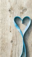 Blue ribbon heart shape on rustic weathered wood background for romantic greeting cards, wedding invitations and love themed designs.