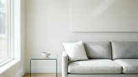 Minimalist living room interior with light gray upholstered sofa, white and gray pillows, small side table, and natural window light for home decor and interior design projects.
