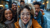 Happy diverse young adults taking selfie on city street at night with warm lights and cheerful expressions for social media and friendship concepts.