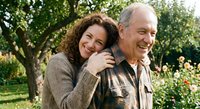 Happy mature Caucasian couple embracing outdoors in garden setting, showing love and affection in golden hour light for relationship and lifestyle content.
