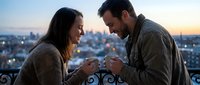 Young couple holding engagement ring on rooftop at sunset with city skyline, romantic proposal moment, relationship milestone celebration.