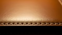 Close-up of brown leather material with decorative stitching detail showing craftsmanship and texture for luxury goods manufacturing and design projects.