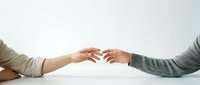 Two people reaching toward each other with outstretched hands in gentle touching gesture, symbolizing connection, support and human interaction on clean background.