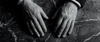Professional businessman hands on dark marble surface in black and white monochrome style for corporate business concepts and executive presentations.