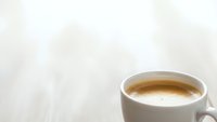 Fresh espresso coffee in white ceramic cup on light textured background with copy space for morning beverage and cafe concepts.