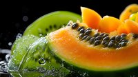 Fresh papaya and kiwi slices with water drops on dark background, macro shot showing juicy tropical fruit texture and vibrant colors for food photography.
