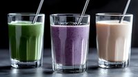 Colorful healthy smoothies in glasses with metal straws - green vegetable, purple berry, and pink protein drinks on dark background. Fresh detox beverages.