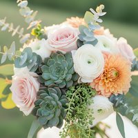 Elegant bridal bouquet with pink roses, white ranunculus, orange dahlia and green succulents for wedding ceremony and romantic celebrations.