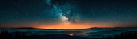 Panoramic night landscape with vibrant Milky Way galaxy over mountain silhouettes and glowing orange horizon, stars reflecting in calm lake waters below.