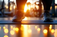 Athletic shoes on yoga mat at sunset with golden bokeh lights reflecting on wet surface, creating peaceful atmosphere for mindful fitness practice and wellness routine.