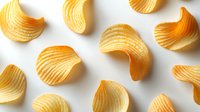 Crispy potato chips with ridged texture scattered on white background, golden yellow color with distinctive wavy pattern. Fresh snack food photography.