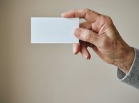 Senior male hand holding blank white business card against neutral background for corporate branding and professional identity mockup purposes.