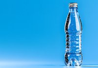 Clear plastic water bottle with liquid against vibrant blue background, minimalist composition showing purity and refreshment. Clean modern product photography.