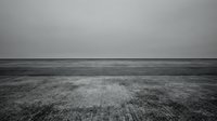 Minimalist black and white landscape with empty field stretching to horizon under overcast sky creating moody atmospheric scene for backgrounds.