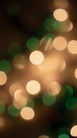 Abstract bokeh lights background with warm golden and green circular blur effects creating dreamy atmospheric mood for holiday celebrations and festive designs.