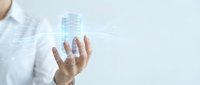 Businessman holding smartphone with glowing digital building hologram, smart city technology concept, futuristic architecture visualization on light background.