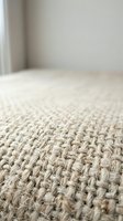 Natural jute carpet texture close-up with woven fiber pattern on neutral background for interior design and home decor projects.