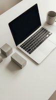 Modern minimalist workspace with open laptop, concrete blocks and ceramic mug on white desk. Clean office setup for productivity and remote work concepts.