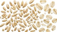 Organic oat flakes and grains scattered on white background. Natural breakfast cereal ingredients for healthy nutrition and cooking recipes.