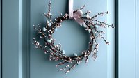 Delicate spring wreath with white cherry blossoms and pink ribbon hanging on light blue door creates welcoming seasonal home entrance decor.