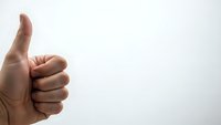 Human hand showing thumbs up gesture against white background expressing approval, success and positive feedback for business presentations.