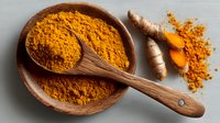 Vibrant turmeric powder in wooden bowl with spoon and fresh root. Aromatic spice for cooking, natural food coloring, and traditional medicine.