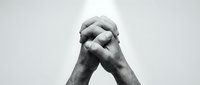 Two hands clasped together in prayer or meditation pose against clean white background. Black and white monochrome style for spiritual concepts.