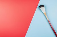 Makeup brush on diagonal split color background of coral pink and light blue. Minimal cosmetic flatlay composition with copy space for beauty content.
