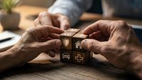 Senior hands protecting wooden blocks with insurance symbols including shield, car, home and medical cross representing comprehensive coverage and financial security.