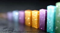 Colorful chalk pieces arranged in row with soft bokeh effect and shallow depth of field creating artistic composition on dark textured background.