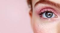 Close up macro shot of blue eye with pink glitter eyeshadow and shimmer makeup on clean skin. Professional beauty cosmetics and glamour fashion photography.
